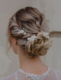 a woman with her hair in a low bun and some flowers on the back of her head