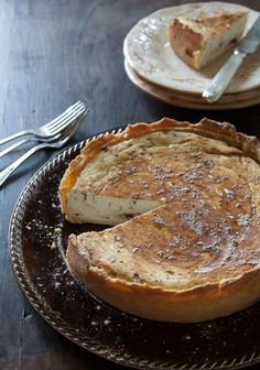 a pie sitting on top of a wooden table next to two plates with silverware