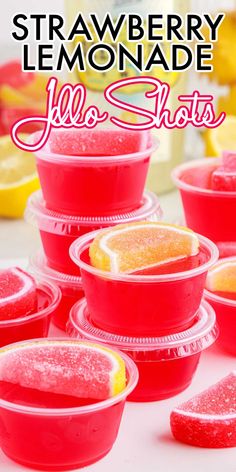 strawberry lemonade jello shots in plastic cups with strawberries and lemons on the side