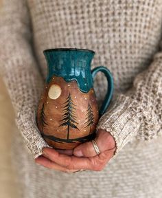 a person holding a ceramic mug in their hands