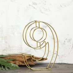 a gold metal object sitting on top of a wooden table next to leaves and branches