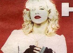 a woman with blonde hair and red lipstick holding a black object in her hands, against a red background