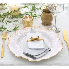 a place setting with napkins, silverware and gold cutlery on a white table cloth