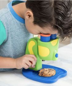 a young boy looking through a microscope at a cookie