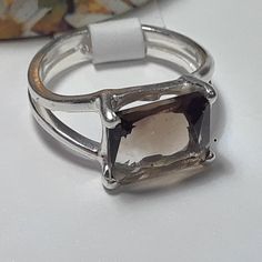 This Simple Sideways Set Ring Features A 10x8mm Emerald Cut Smokey Topaz, Set With 4 Sterling Prongs. The Mounting Is A Split Shank, And Measures Aprox 3/8" In Width & Weighs Aprox 3.439 Grams Of Solid (Stamped 925 Inside The Shank) Sterling Silver. This Simple Sideways Set Smokey Topaz Ring Has A Msrp Of $399.00. Finger Size 6 Classic Silver Rings With Rectangular Stone, Silver Topaz Ring With Rectangular Stone For Promise, Silver Solitaire Ring Gemstone, White Gold Sterling Silver Ring With Rectangular Stone, Octagon Sterling Silver Topaz Anniversary Ring, Silver Octagon Topaz Promise Ring, Octagon Topaz Ring In Sterling Silver For Anniversary, Modern Silver Topaz Ring With Emerald Cut, Sterling Silver Octagon Topaz Ring For Anniversary