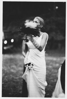 a black and white photo of a woman in a wedding dress holding a flower bouquet