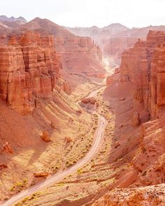 a dirt road in the middle of some rocky hills and canyons with trees on each side