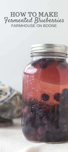 a jar filled with blueberries sitting on top of a table next to a cloth