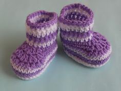 purple and white crocheted baby booties sitting on top of a table