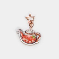 a red teapot charm on a white background