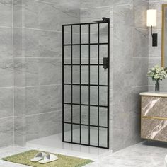 a bathroom with marble walls and flooring has a glass shower door in the corner