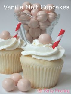 two cupcakes with white frosting and candy sticks in front of the cupcake