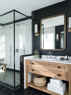 a bathroom with black walls and white tile flooring, two mirrors on the wall