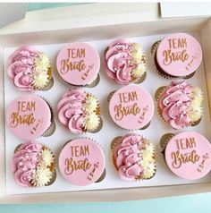 twelve pink and white cupcakes with team bride written on them in a box