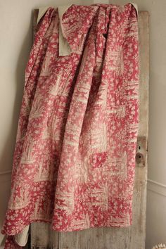 a red and white curtain hanging on the side of a wooden door