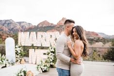 A couple dances to a custom song with the scenic Sedona mountains in the backdrop as the sun sets. Behind them is a large rug where "marry me" marque letters adorned in framing flowers light up. To the side of the marque letters is a mirror with a sentimental note. Concert Proposal, Proposal For Him, Proposal Speech, Elegant Proposal, Summer Proposal, Slow Dancing, White Floral Arrangements, Proposal Design, Neutral Outfits