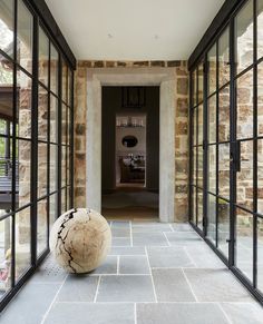 a large vase sitting on top of a stone floor next to glass doors and windows