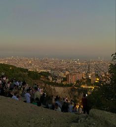 a group of people sitting on top of a hill next to a cityscape