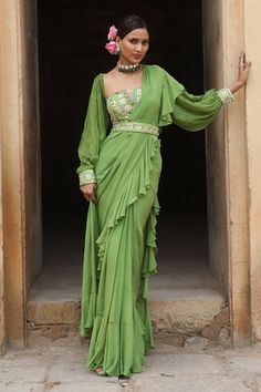 Green pre-draped saree with ruffle detailing crafted in georgette. Comes with embroidered padded bustier and belt.
Components: 3
Pattern: Embroidery
Type Of Work: Cutdana, Nakshi, Mirror, Thread, Beads
Neckline: Straight
Sleeve Type: Balloon Sleeves
Fabric: Uppada Silk, Georgette
Color: Green
Other Details: 
Attached lining
Closure: Saree: Button
Approx weight (in kgs): 2-3
Occasion: Destination Wedding - Aza Fashions Green Drapes, Thread Beads, Green Embroidery, Ruffle Saree, Drape Saree, Beaded Neckline, Silk Embroidery, Fabric Silk, Green Silk