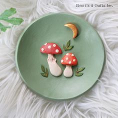 two mushrooms on a green plate with leaves and a half moon painted on it's surface