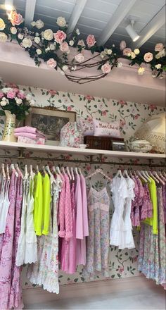 a room filled with lots of clothes and flowers on the wall next to a shelf