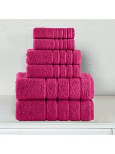 a stack of pink towels sitting on top of a white shelf