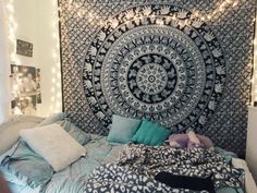 a large tapestry hanging over a bed in a room with lights on the wall behind it