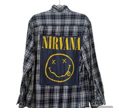 Nirvana  up- cycled Custom Plaid Button Down  - Nirvana logo made from Graphic t shirt   - Size XL men's / unisex  - flat Measurement: pit to pit: 25in / Length: 30in   - yellow and blue   - vintage inspired  This custom made, band tee logo plaid button down is the perfect staple piece for your closet.  It's so cute to wear unbuttoned with a tank under, you can also wear it buttoned up which is just as cute.  The best part about it is it a good transition piece for all seasons.  It looks so cute with short, jeans or even leggings if you are going for more of a casual look. Fall Festival Cotton Shirt, Cotton Festival Shirt For Fall, Cotton Shirt For Alternative Fashion In Fall, Plaid Grunge Tops For Streetwear, Cotton Shirt With Screen Print For Festival, Cotton Screen Print Shirt For Festivals, Cotton Shirt For Festival Streetwear, Vintage Plaid Tops With Graphic Print, Vintage Reworked Plaid Tops