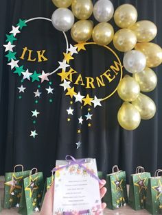 a person holding up a paper card in front of balloons and stars on the wall