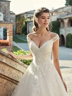 a woman in a wedding dress leaning against a stone wall