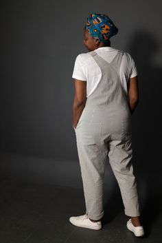 a woman standing with her back to the camera wearing a white shirt and grey pants