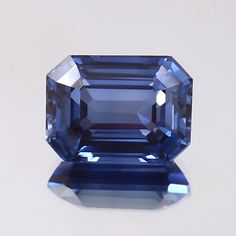 an unhealthy blue sapphire is displayed on a white surface with the light reflecting off it's side