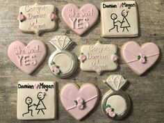 decorated cookies are arranged in the shape of hearts and engagement rings, with congratulations messages on them