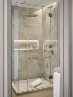 a walk in shower sitting next to a white towel on top of a wooden floor