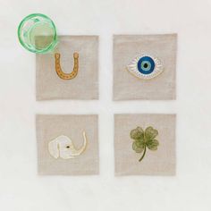 four napkins with embroidered pictures of elephants, an eye and a shamrock on them