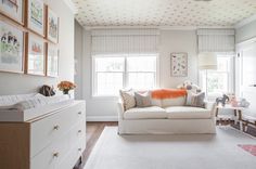 a living room filled with white furniture and lots of window coverings on the walls