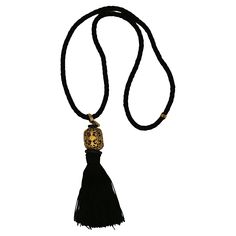 YVES SAINT LAURENT vintage black rope necklace featuring a black tassel topped by a gorgeous openwork gold tone cylinder. Probably designed by MAISON DENEZ for YVES SAINT LAURENT. Embossed YSL. Indicative measurements : wearable length (excluding the pendant) approx. 29 cm (11.42 inches) / height of the pendant (including tassel) approx. 11.5 cm (4.53 inches). Materials : Rope / Tassel / Gold tone metal / Wood / Resin. NOTES - This is a preloved vintage item, therefore it might have imperfections. - Colors may differ slightly from actual product appearance due to differences in lighting conditions. - As a buyer, you are fully responsible for customs duties, other local taxes and any administrative procedures related to imports into the country of destination. Black Rope Necklace, Rope Tassel, Saint Laurent Vintage, Tassel Top, Black Rope, Brooch Necklace, Disc Pendant, Wood Resin, Beaded Choker Necklace