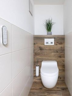 a white toilet sitting inside of a bathroom next to a plant