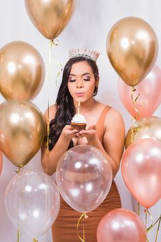 a woman holding a cupcake in front of balloons