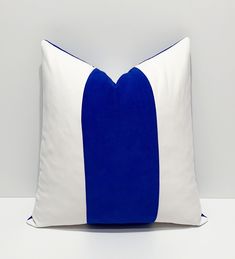 a blue and white pillow sitting on top of a white table next to a wall