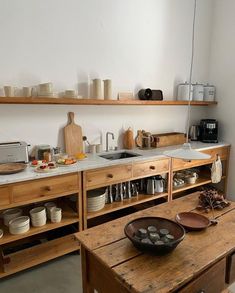 a wooden table topped with lots of bowls and pans filled with food next to shelves