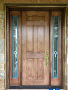 a wooden front door with blue glass panels