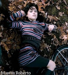 a woman laying on the ground next to a bike with leaves all over her body