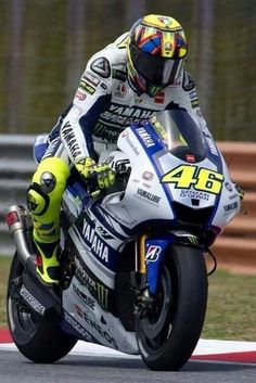 a man riding on the back of a motorcycle down a race track