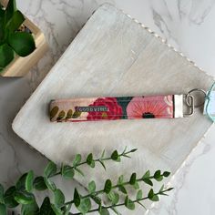 a keychain with a flower print on it sitting next to a green plant