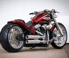 a red motorcycle parked in front of a white wall with chrome rims on it