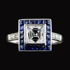 METAL SPECIFICATIONS White Gold 14K STONE SPECIFICATIONS Stone Name : Diamond and Blue Sapphire Stone Cut : Asscher, Round and Trapezoid Stone Details : There is one asscher cut old miner diamond approx. 3.50 carats (Approx. Size 7.5 x 7.5 mm) and approx. 1.50 carats of smaller stones on the sides. Natural earth mined stones. Color : F/G Clarity : VS1 Quality of Sapphires : AAA Sapphire Treatment : Heated Total : Approx. 5 Carats RING SPECIFICATIONS Size : 6.5 (Can ship in any size) Appraised Va 5 Carat Ring, Asscher Diamond, Asscher Cut, Blue Sapphire Rings, Sapphire Stone, Natural Earth, Stone Cuts, Halo Rings, Real Diamonds