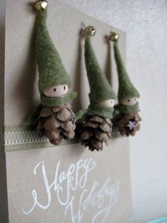 three little gnomes with pine cones on their heads are hanging from a wall ornament