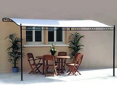 a table and chairs under an awning on a patio with potted plants in the background