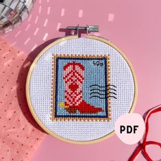 a cross stitch pattern on a pink background with scissors and thread in the foreground